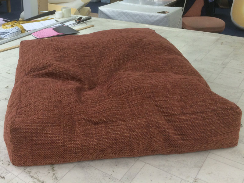 A worn furniture cusion arrives requiring a new foam and fibre filling to restore comfort and shape